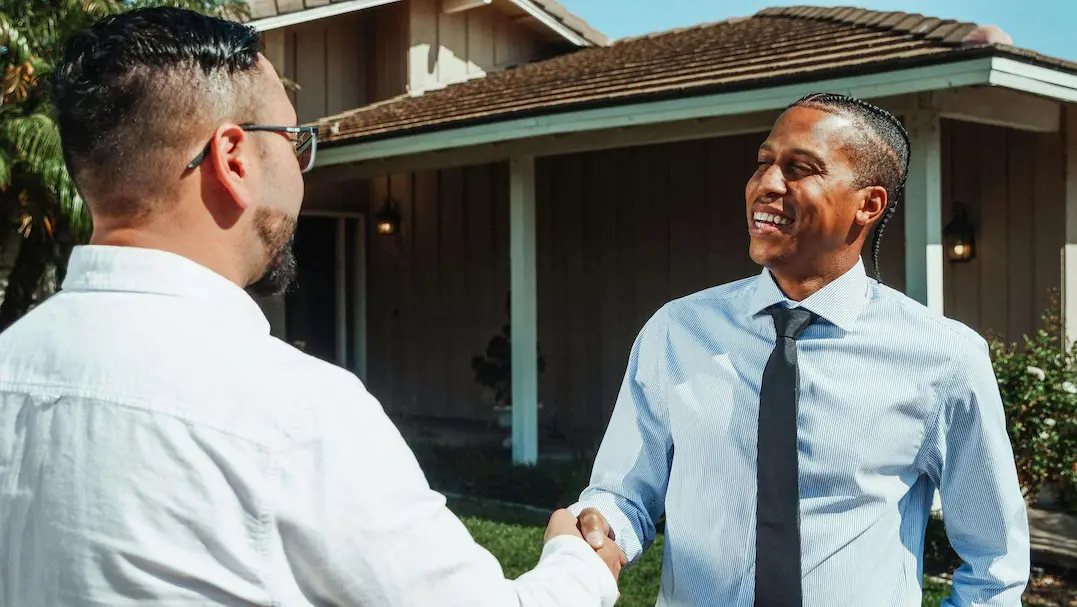 two men shaking hands outside a residence