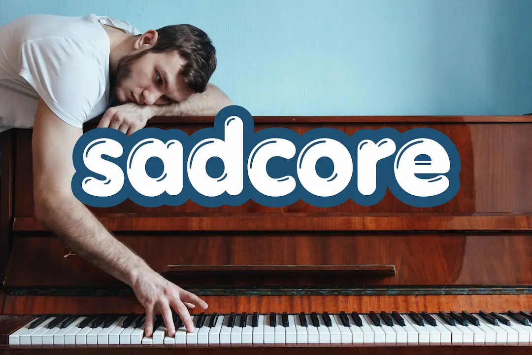 man with pensive expression laying on top of a piano with one hand on the keys